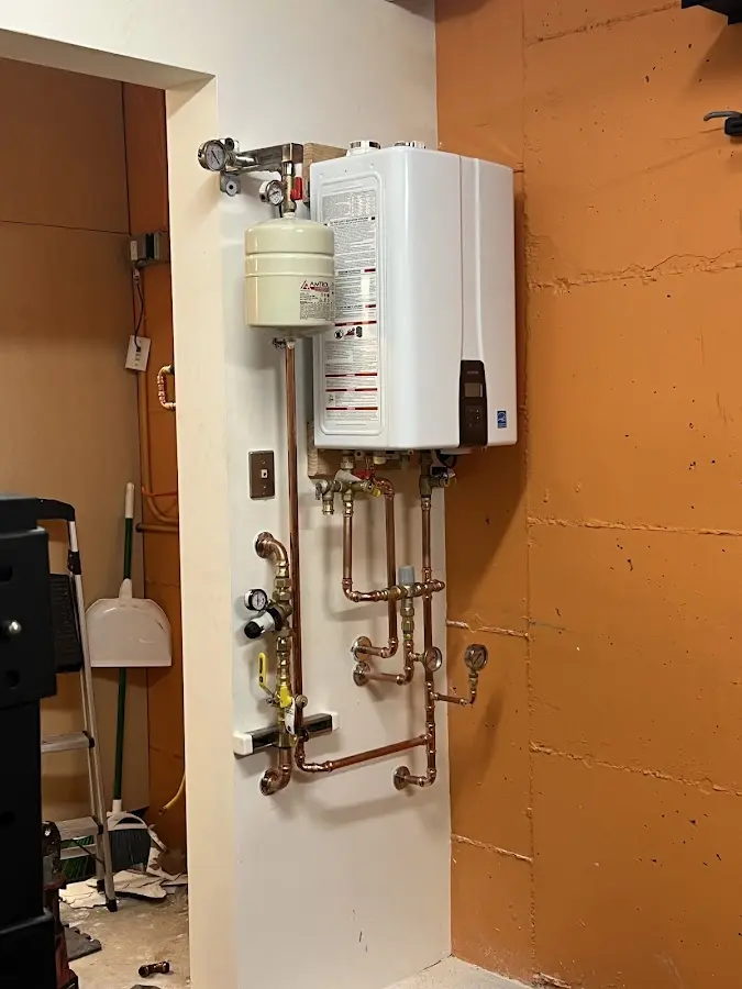 Plumbing technician inspecting water heater connections in Grafton